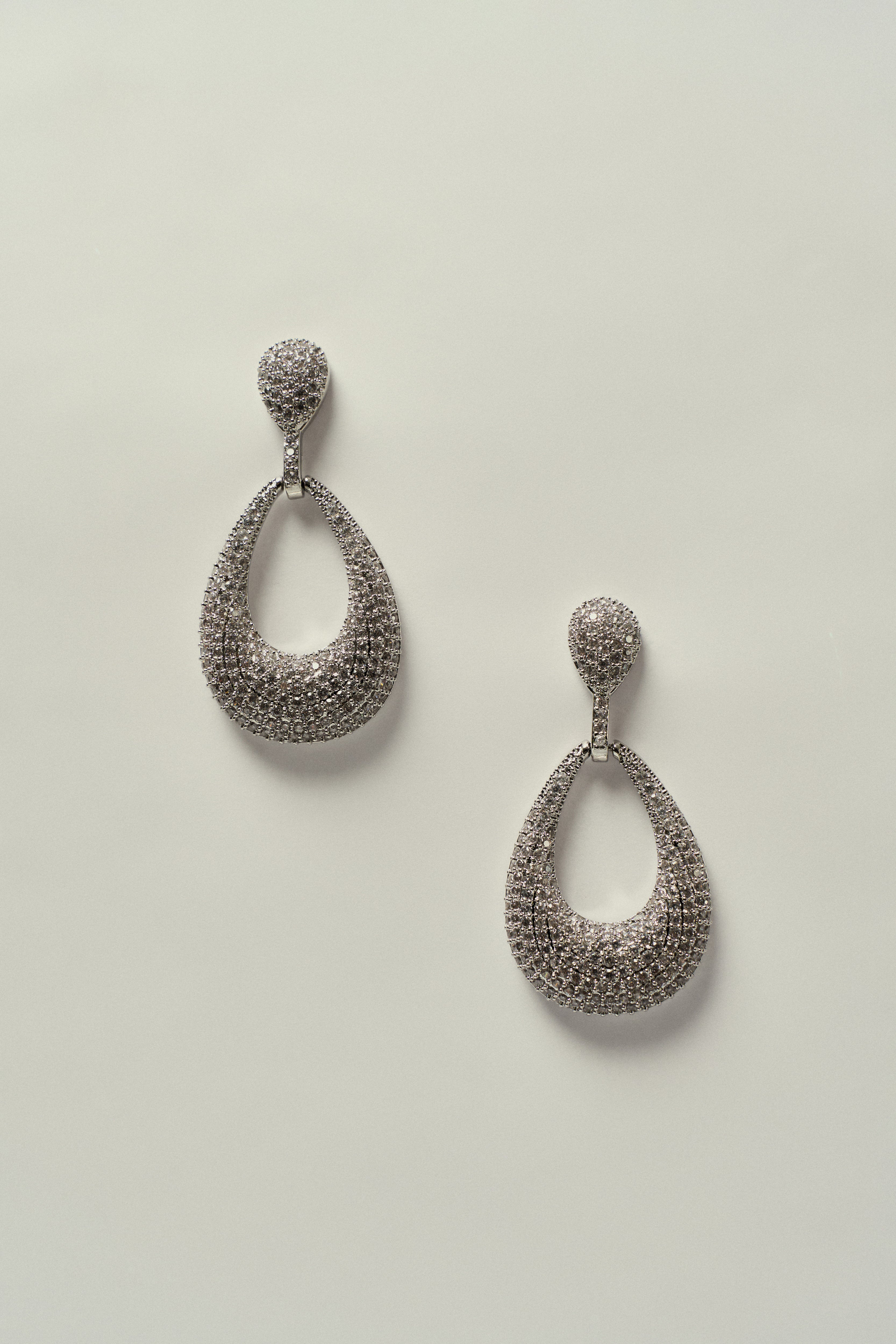 Brinco Oval Vazado Cravejado de Strass Prateado
