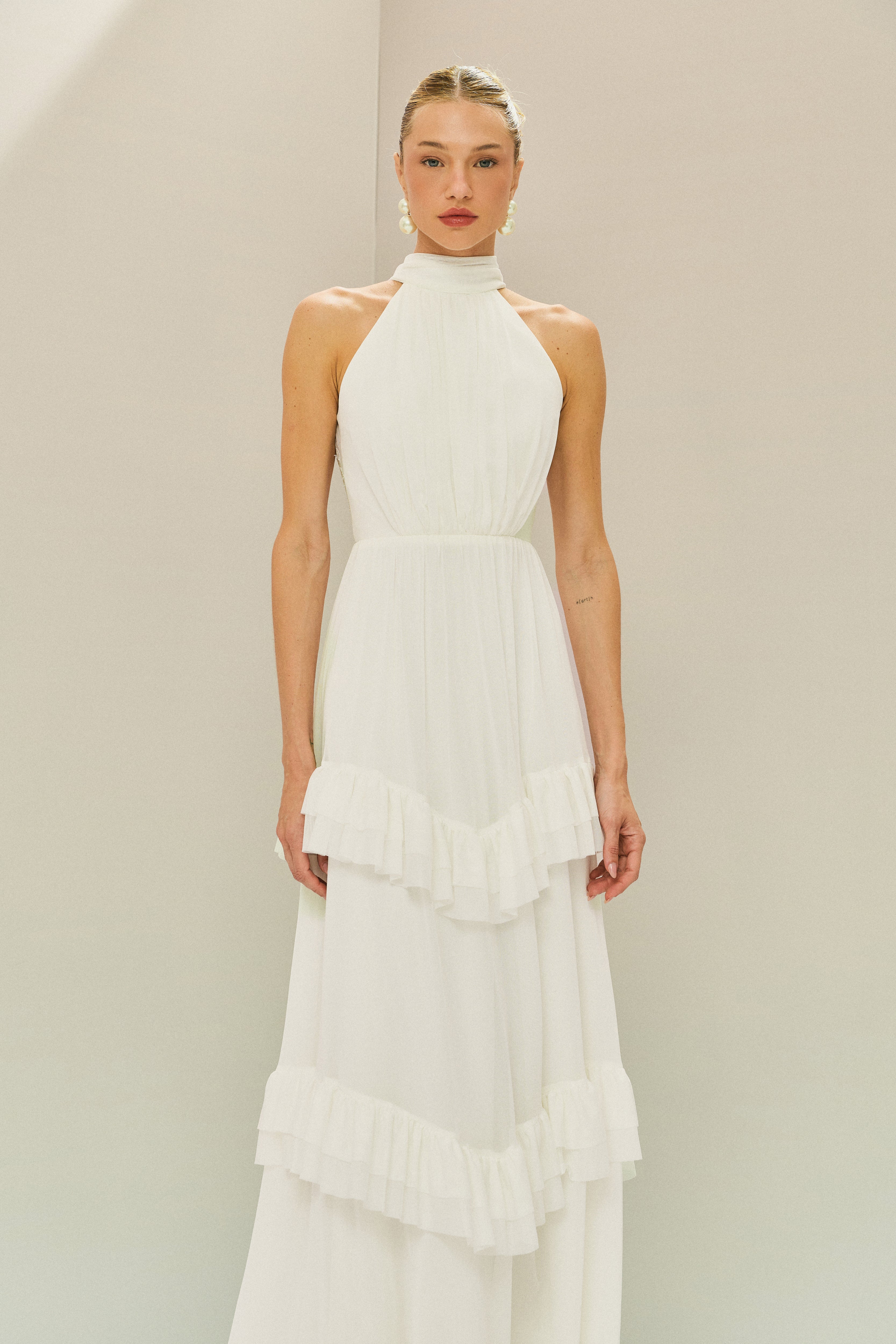 Vestido Longo em Tule com Gola Alta, Costas Abertas com Aplicação de Renda Guipir e Saia em Camadas com Babados - Mons Off White