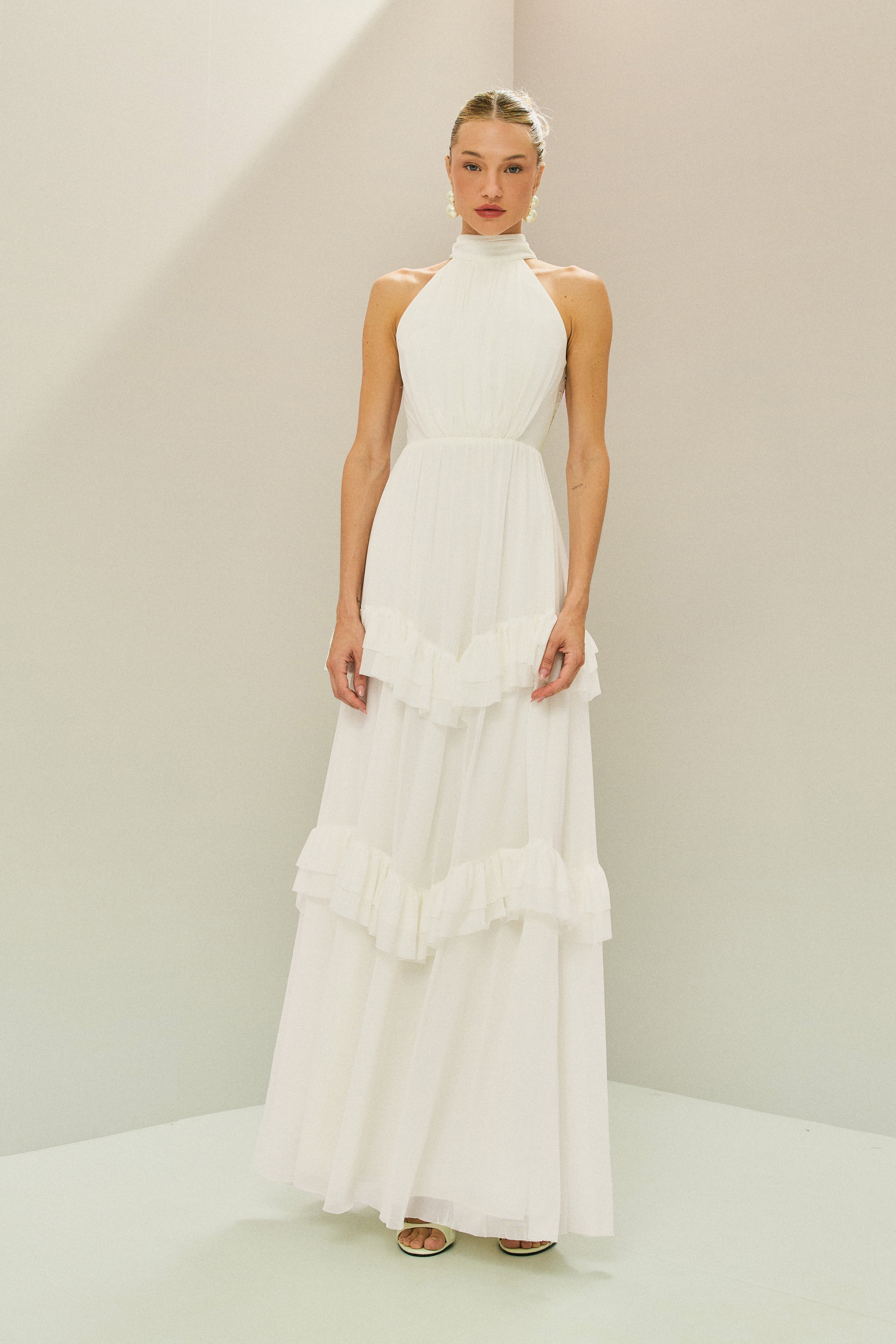 Vestido Longo em Tule com Gola Alta, Costas Abertas com Aplicação de Renda Guipir e Saia em Camadas com Babados - Mons Off White